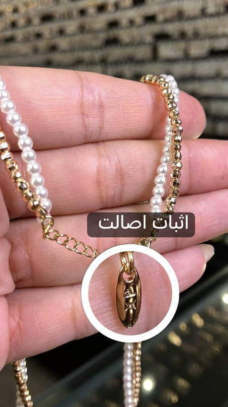 تصویر نمای نزدیک حک لیزری نشان اصالت XP روی قفل گردنبند ژوپینگ مدل البرناردو با دو ردیف مرواریدهای ریز سفید و گویهای طلایی
